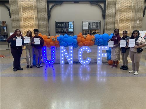  students posing with their certificates and the UNCF light up letters